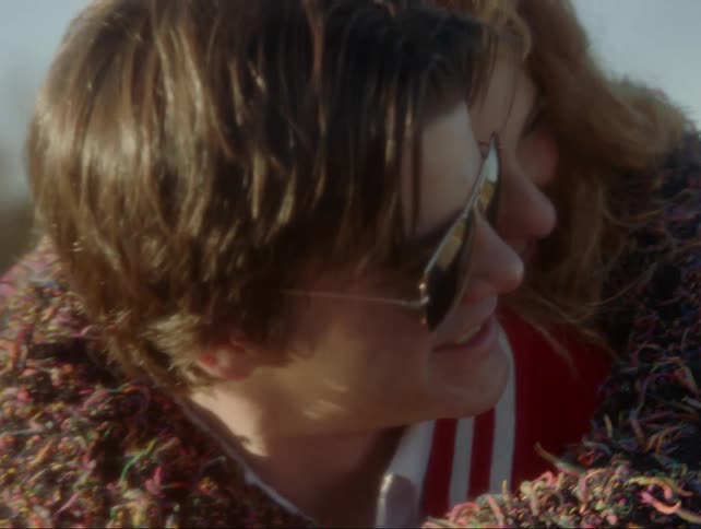 A girl hugs a boy from behind as they both laugh