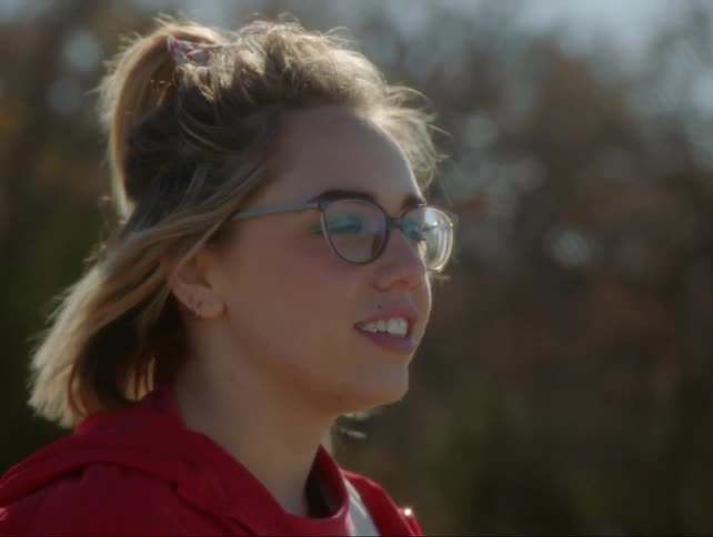 Girl smiles and chews gum as wind blows in her hair