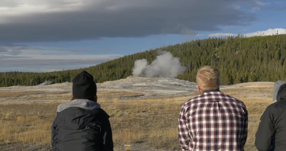 People watch a geyser on an overcast day