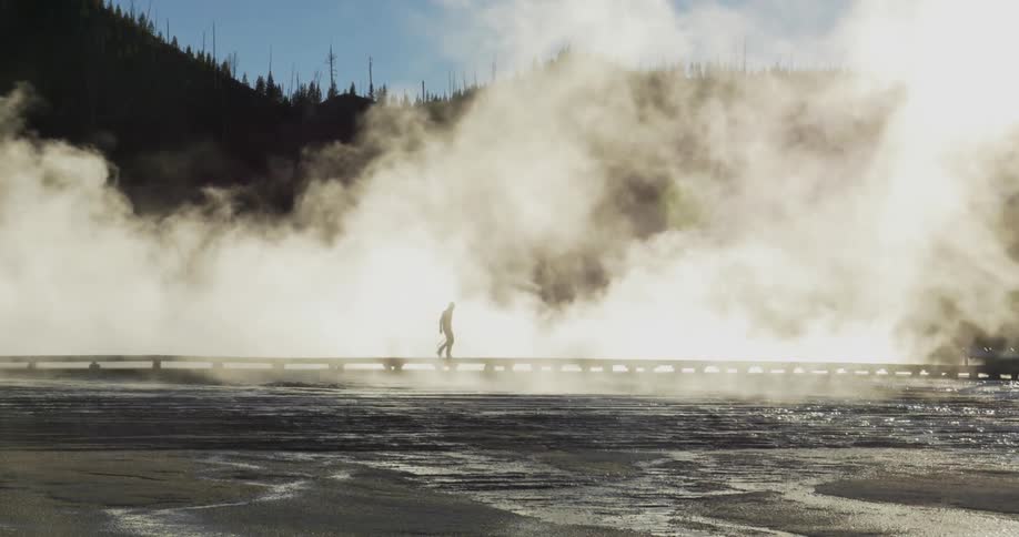 Man walking across a platform as smoke rises around him