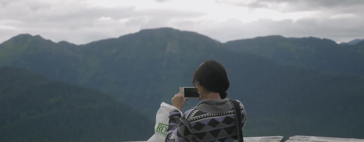 Woman takes pictures of mountains on her phone