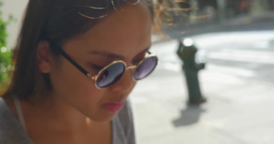 An asian woman wearing sunglasses uses chopsticks to eat with