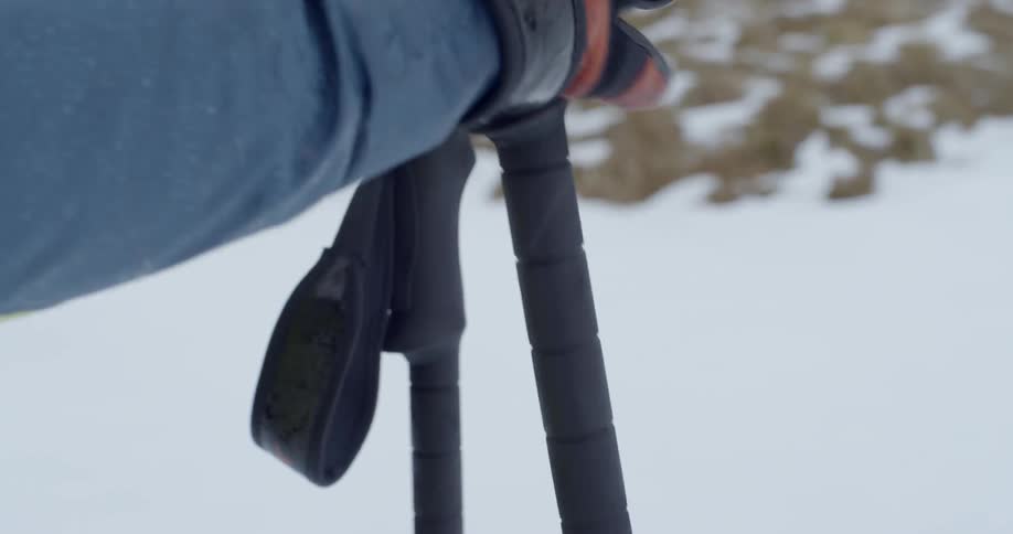 A woman grips ski pole outside in the snow
