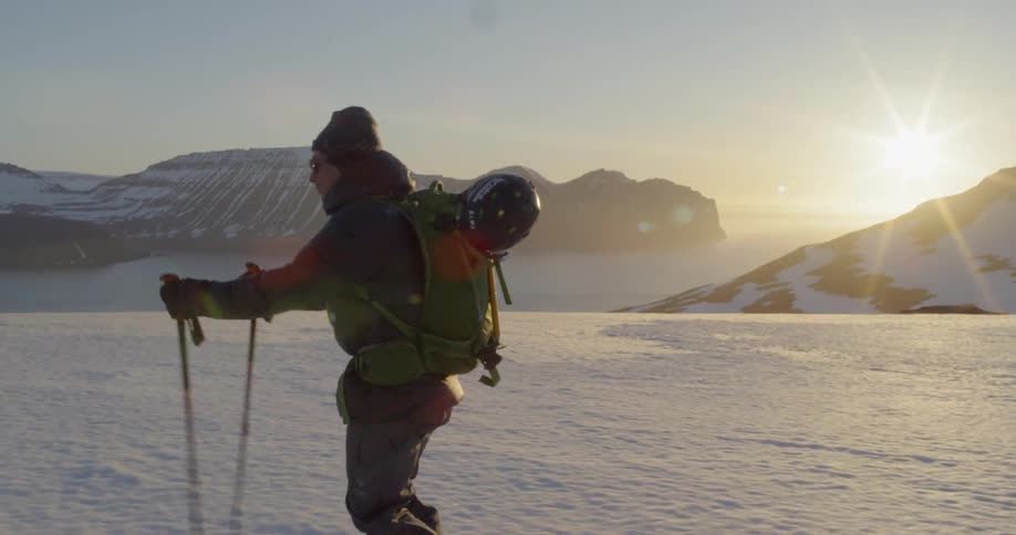 Man glides down snow casually at sunset