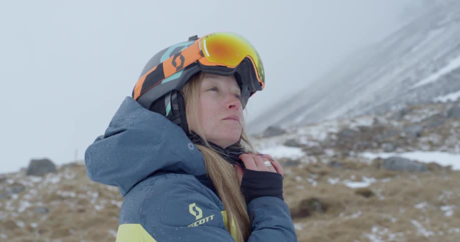 A woman puts on her ski helmet and goggles