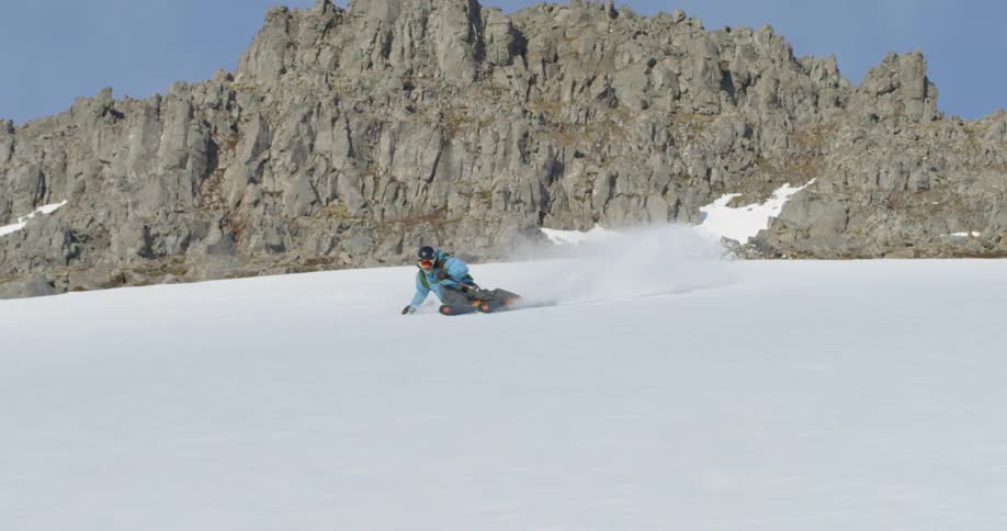 A skier makes an aggressive turn down a snowy mountainside