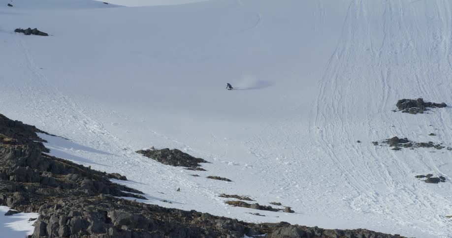 Person skiing fast down a steep mountain slope covered in snow