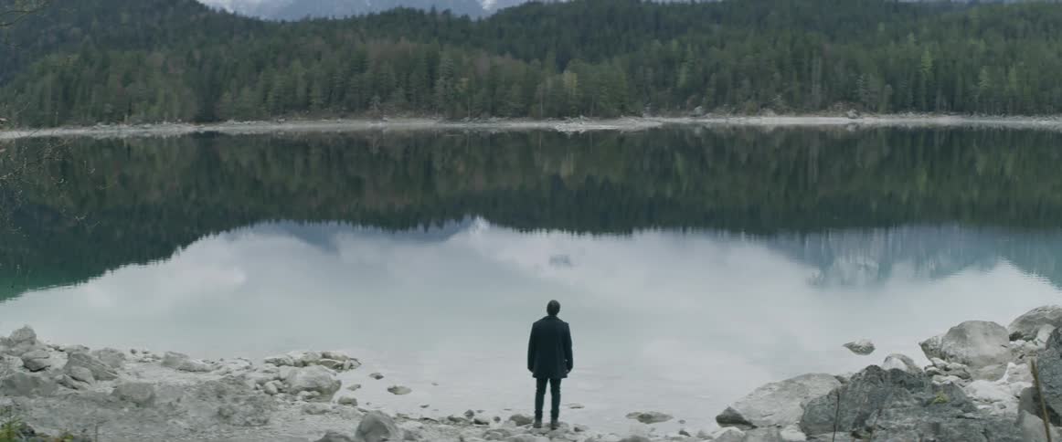 A man is walking down to the edge of a lake
