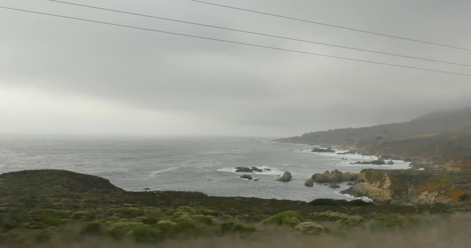 A view of the ocean, shoreline and cliffs under a cloudy sky