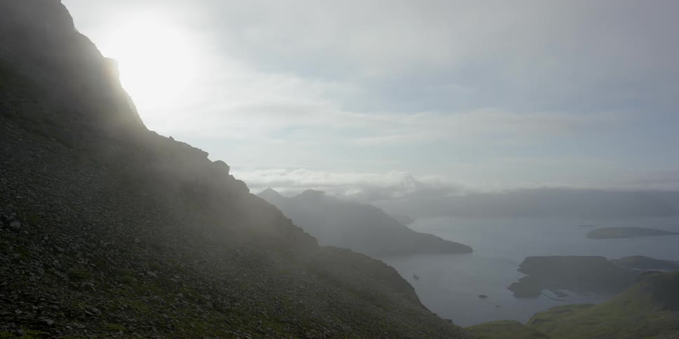 Clouds hover over ocean bay surrounded by mountains