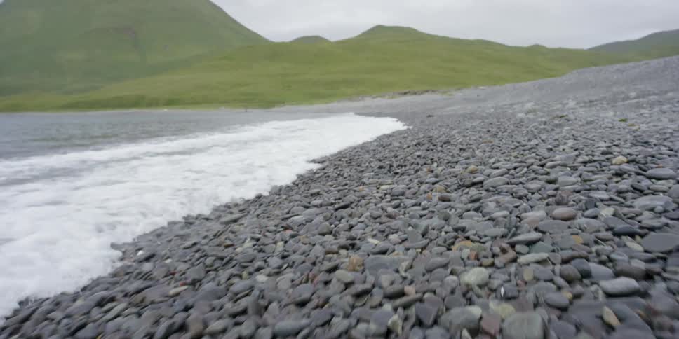 Waves are crashing on a rock covered beach