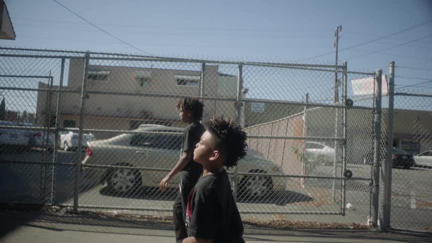 Boys walk past a fenced parking lot