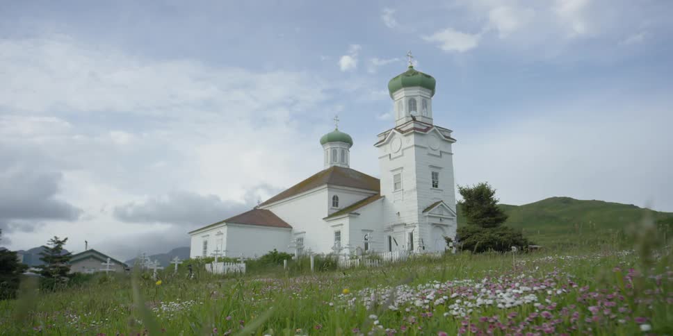 A small church is nestled on a green hillside
