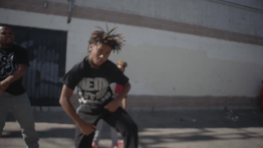 Kids are dancing behind a large building