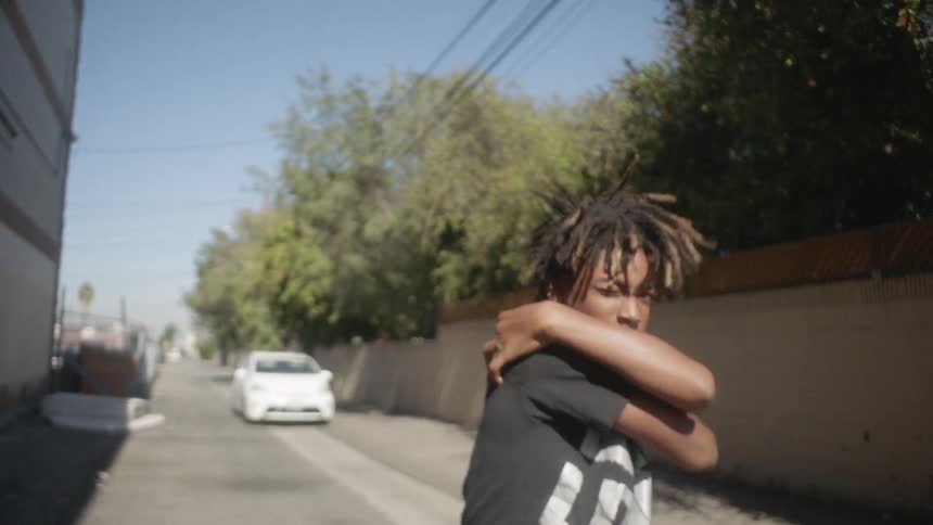 Boy dances near a dumpster