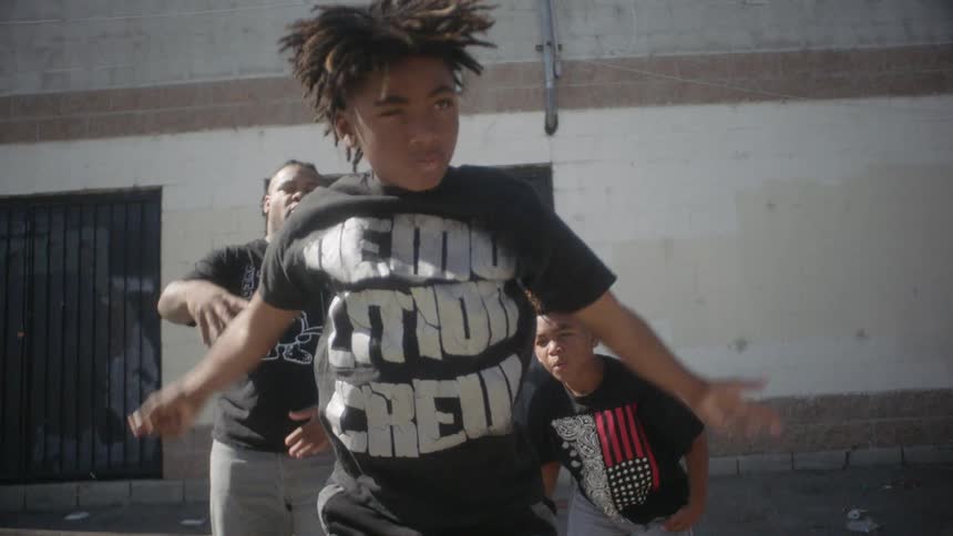 Boys and a man dance in an alleyway