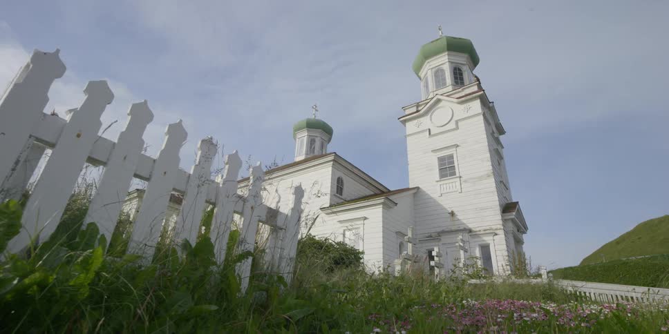 Clouds hover in the sky above a church and graveyard during the day