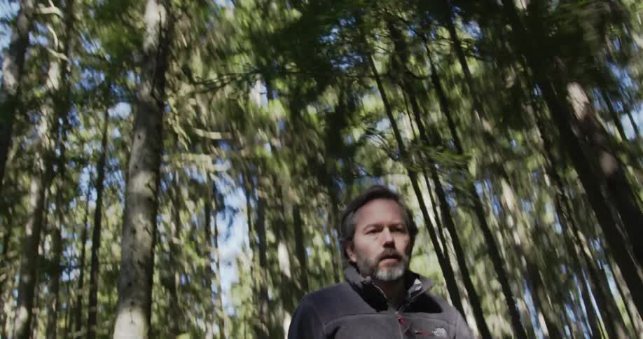Man running and looking behind him in a forest