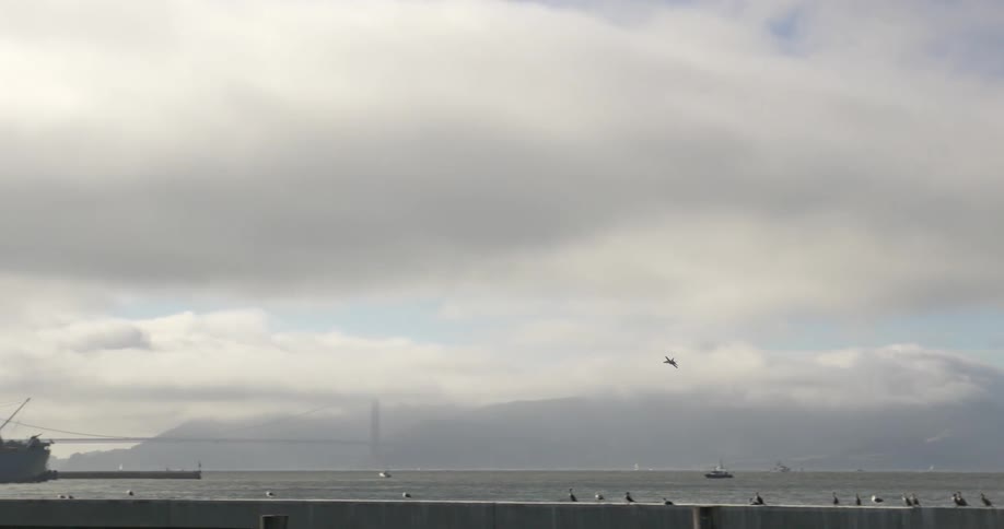 A jet flying toward an aircraft carrier