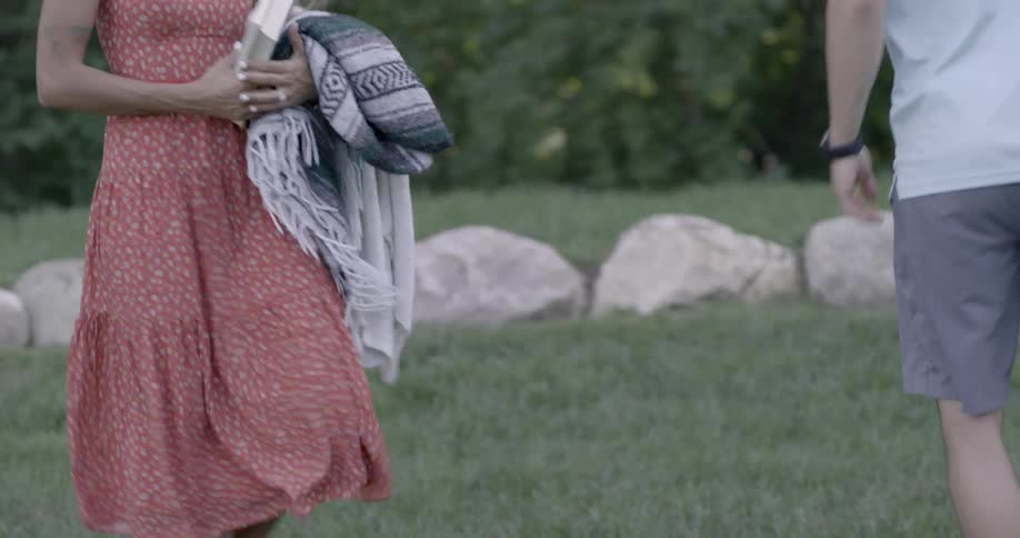 A couple walk on the field and set up a picnic