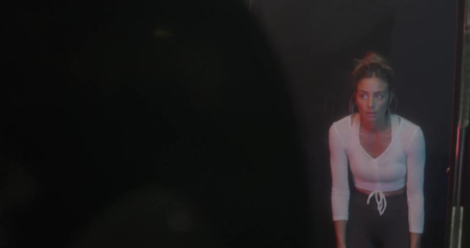 A woman looks at herself in a mirror and leans over