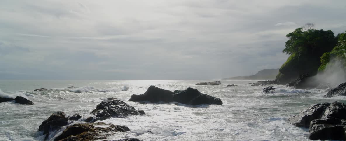 Waves are crashing over rocks on a beach