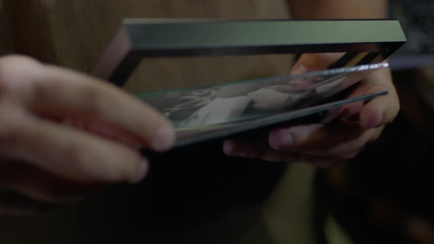 Someone takes a picture out of its frame and examines it