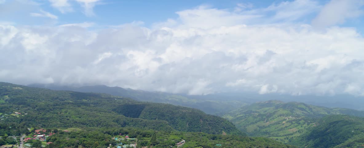 White clouds hang above a green mountain landscape