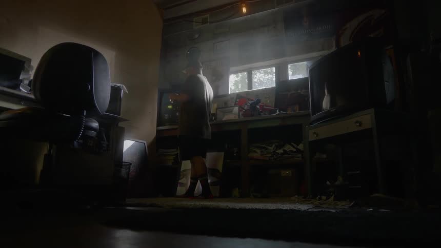 A man is walking back and forth in the dark room