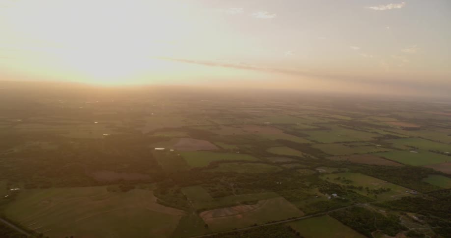 The sun is setting over farm fields