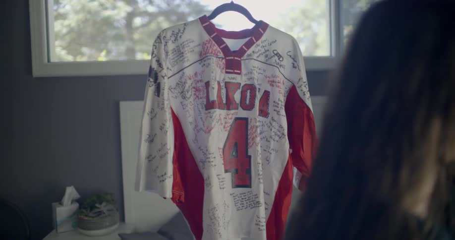 A woman is hanging up a jersey that has a bunch of signatures on it
