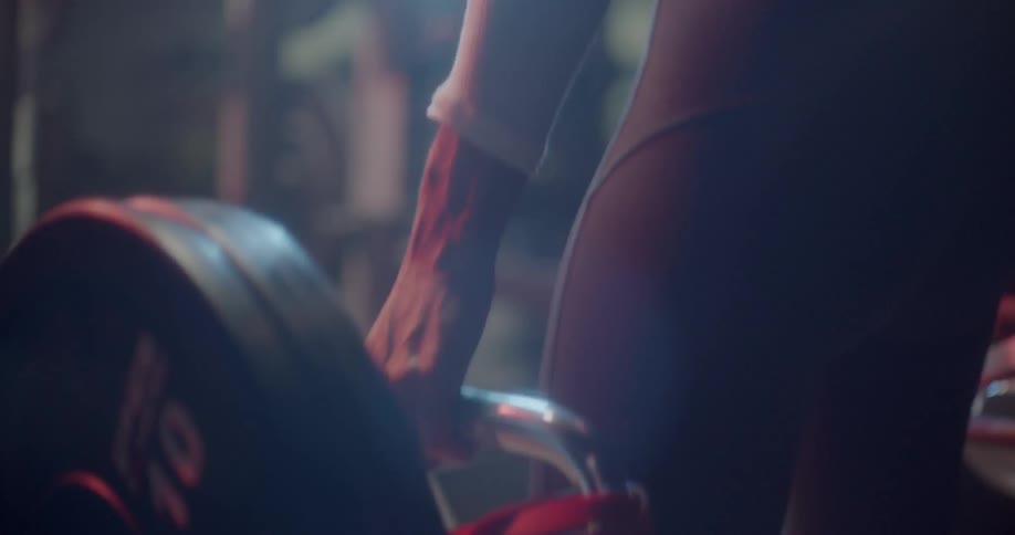 A woman is lifting weights in the gym while looking in a mirror