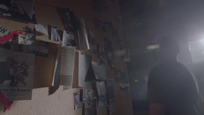 A man is taking down a picture hanging on postboard in a room during the day