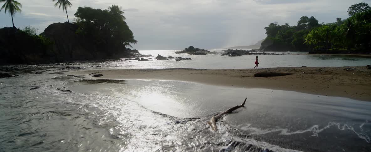 A woman walks on a sandy beach