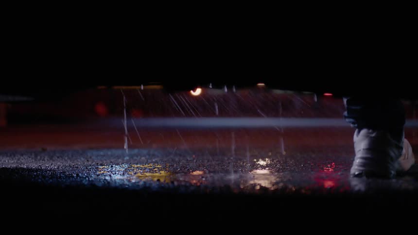 A man gets out of a car and walks away on a rainy night