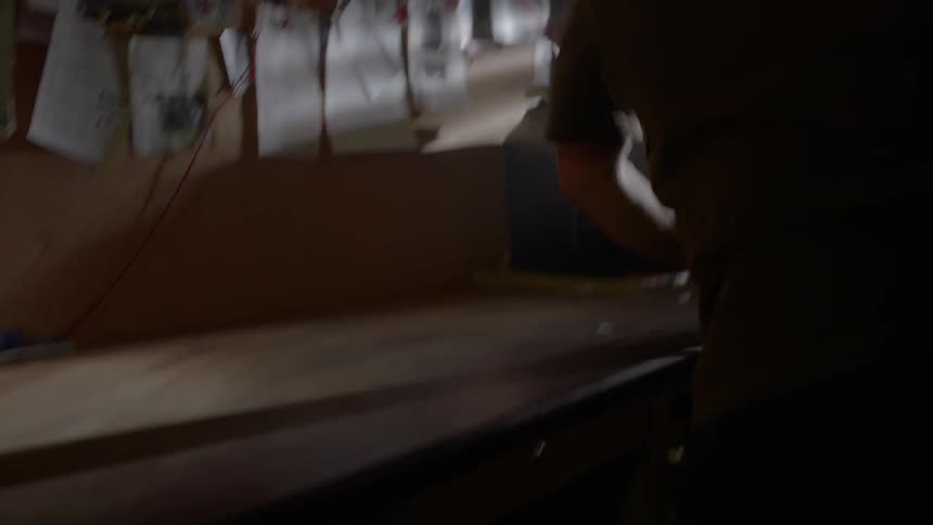 A man pushes all papers off a table then puts a case down