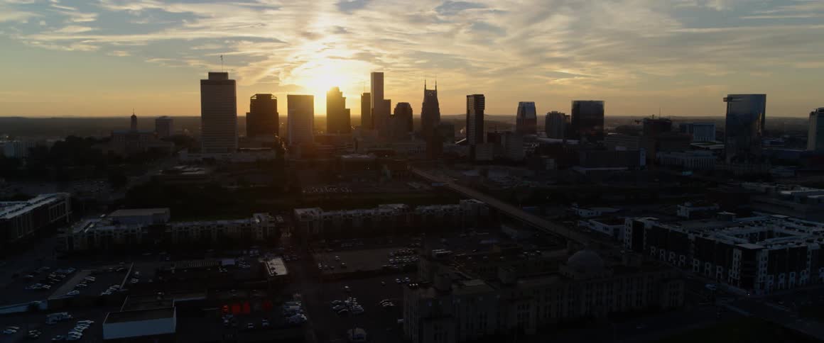 The sun is setting behind the tall buildings