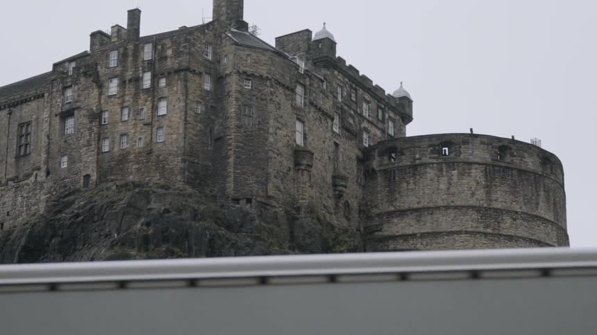 A large castle on a mountainside is viewed from below