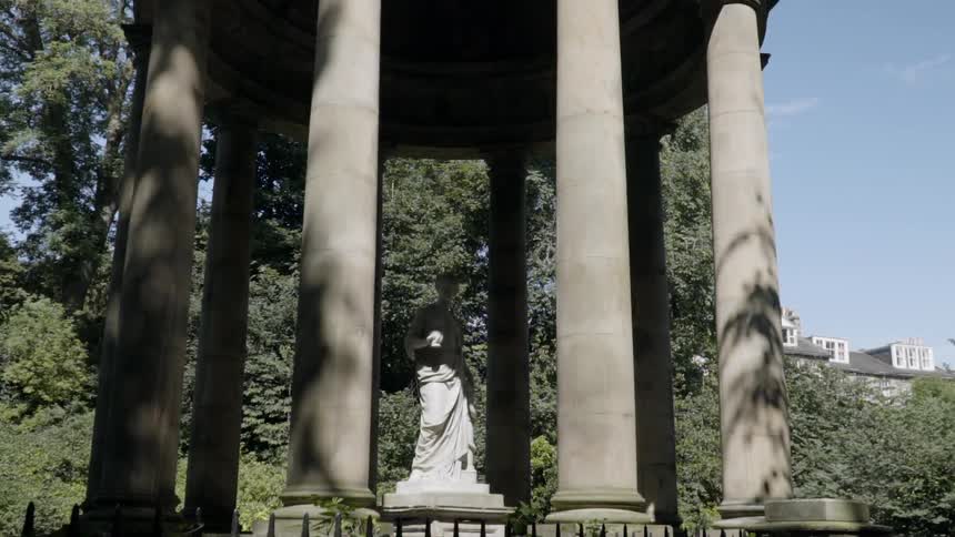 A statue is surrounded by pillars in a park