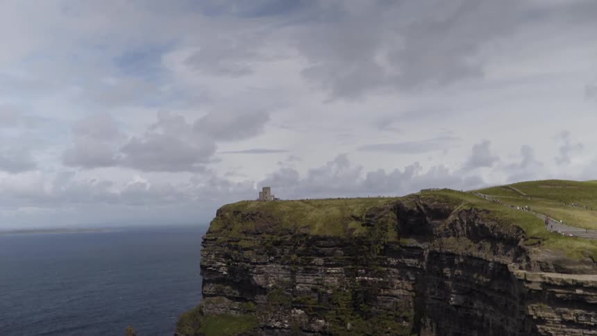 Clouds hang above a tall cliff by the ocean