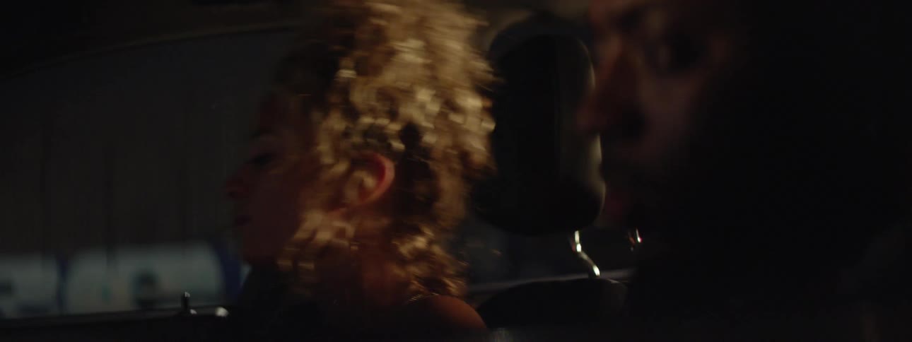 A man and woman are sitting in a car at night