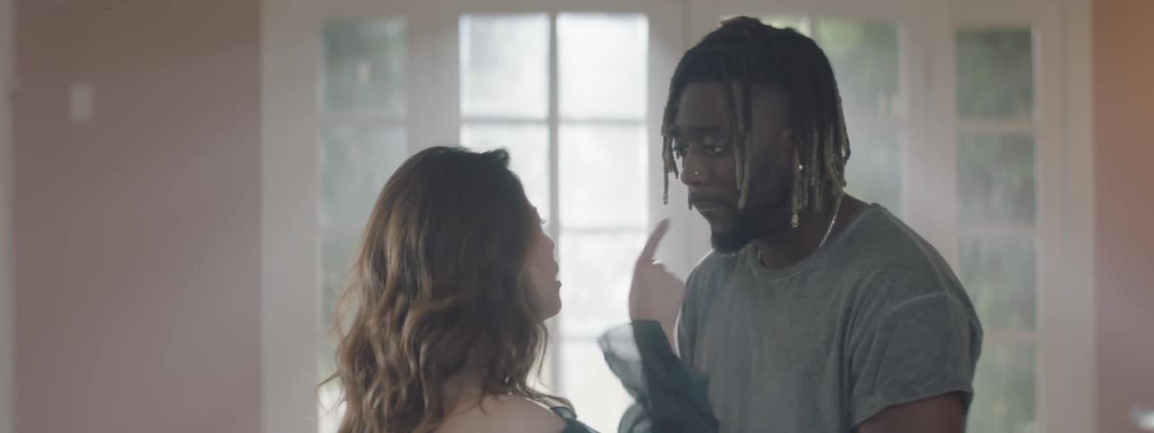 A man and woman argue by a window