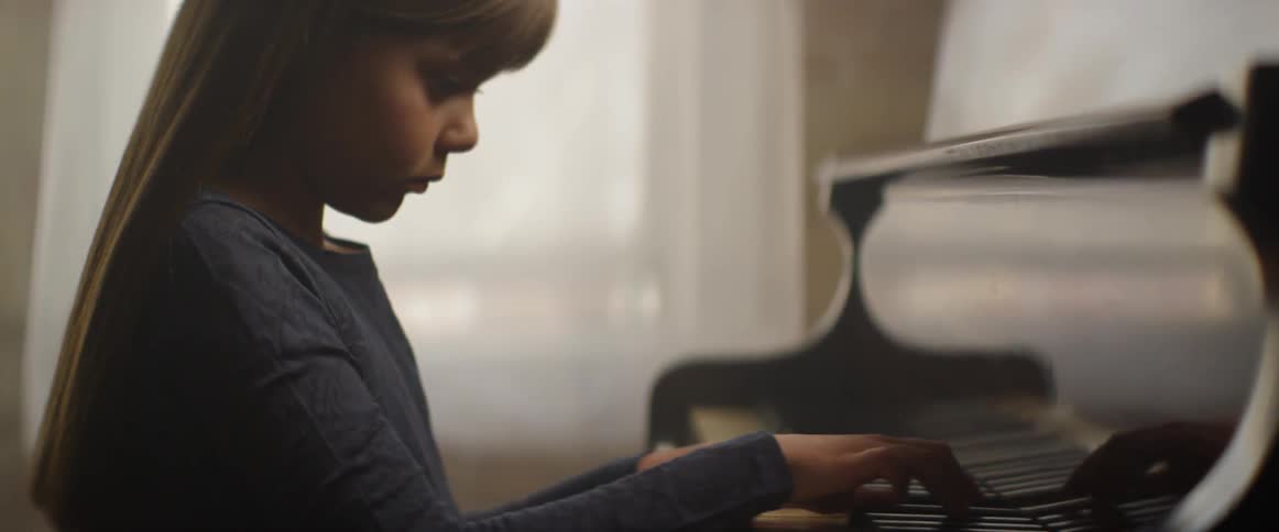 A young girl plays a piano