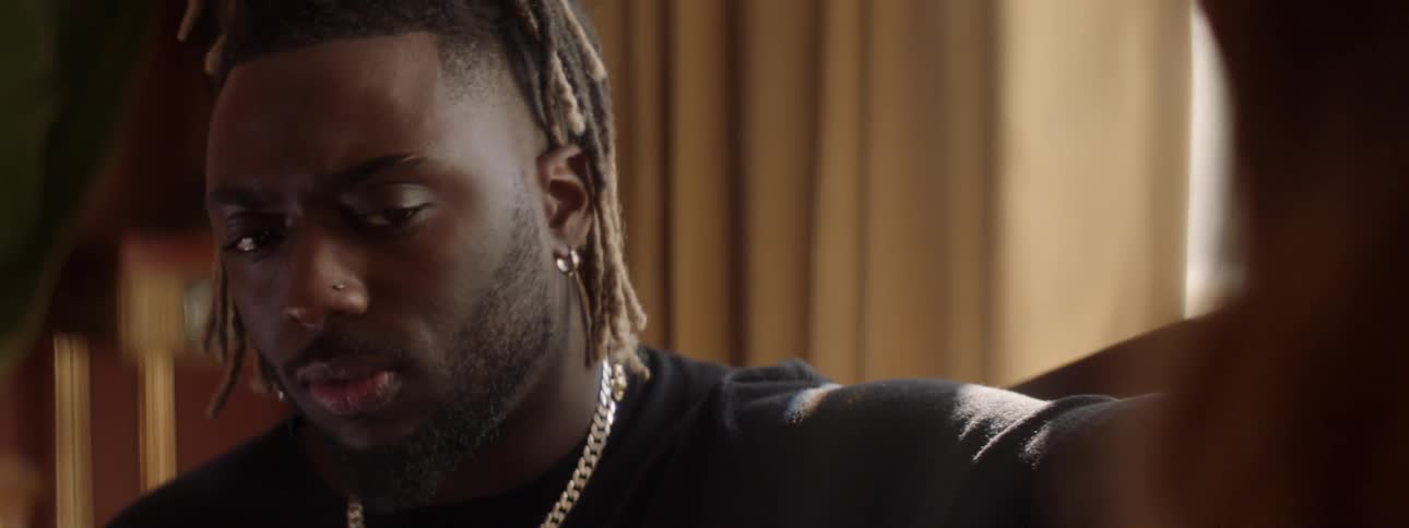 A man with dreadlocks is looking at something off camera with confusion