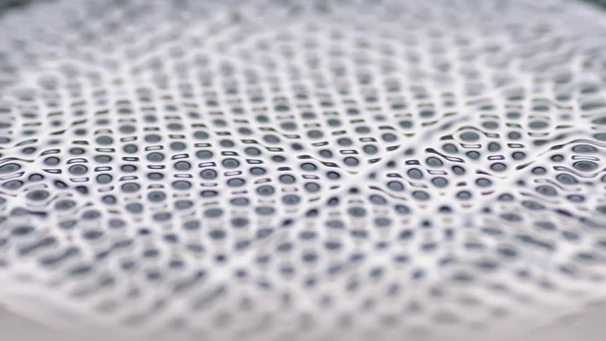 A piece of white fabric with holes in it is vibrating