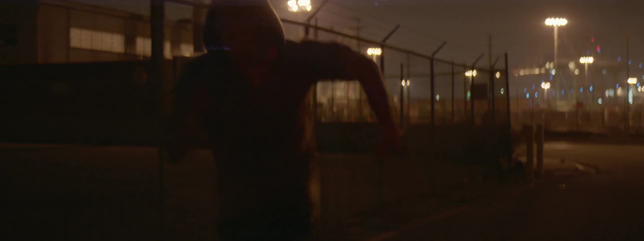An athlete is running in an industrial area at night