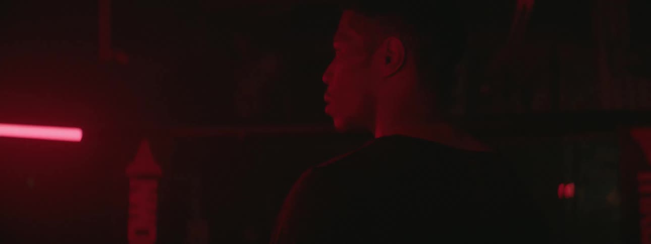 A man stands near red fluorescent lights