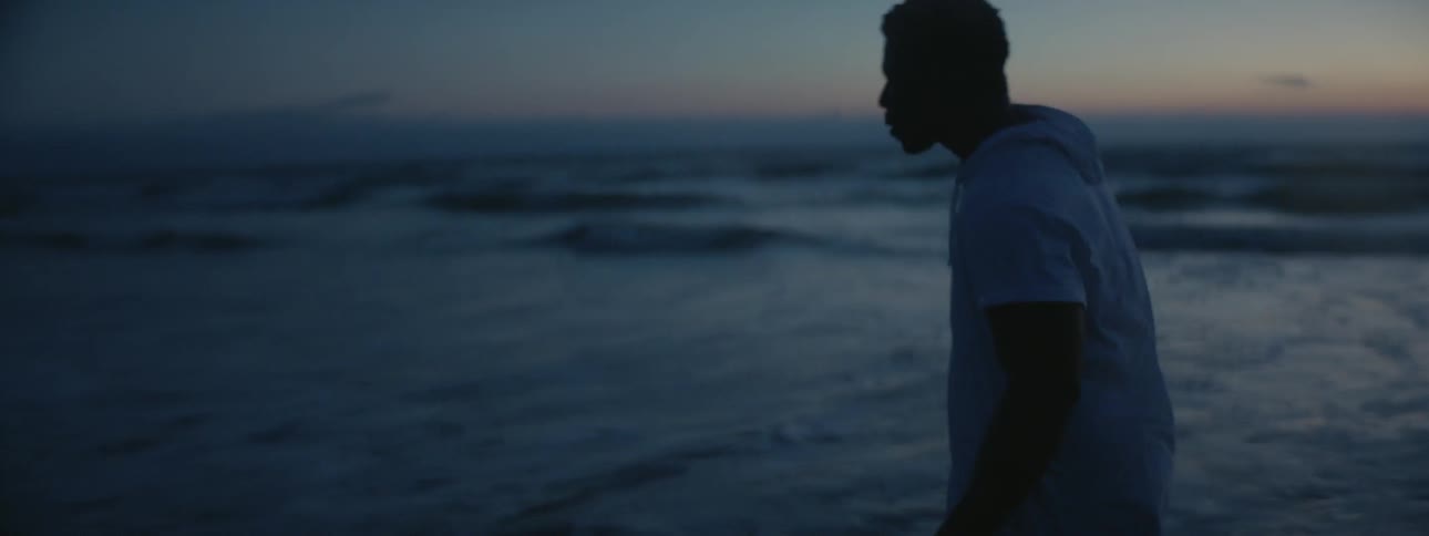 A man walks into the ocean water at dusk