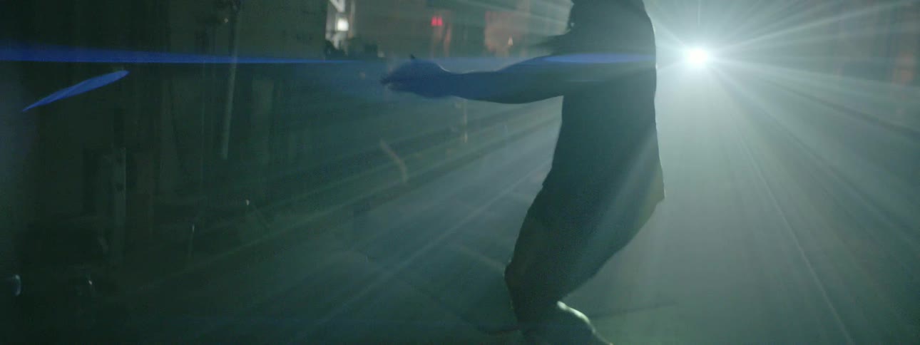 A man spins and kicks in front of a bright light