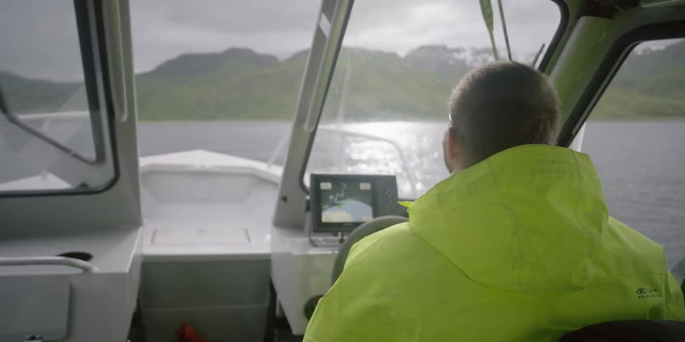 A man is steering a boat in the ocean
